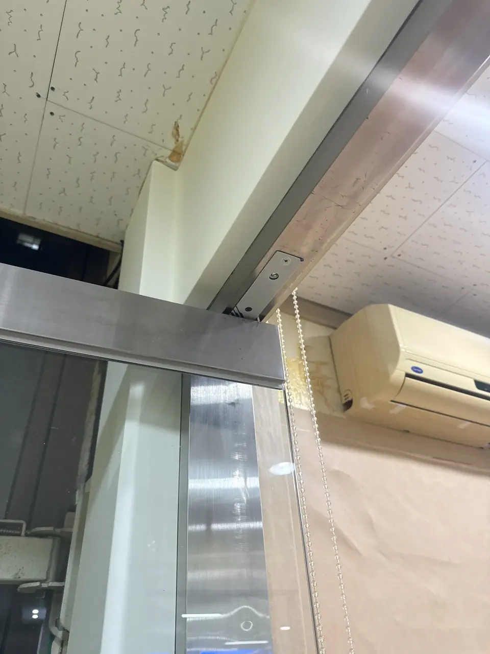 강화유리문 상단 상롯트(피벗 브래킷)와 천장 프레임 접합부 근접 사진